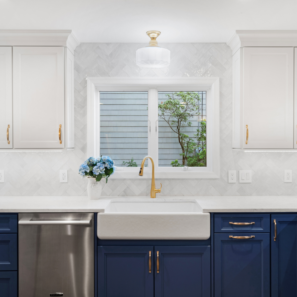 Modern kitchen remodel in Scotch Plains featuring navy blue base cabinets, white farmhouse sink, and gold fixtures.